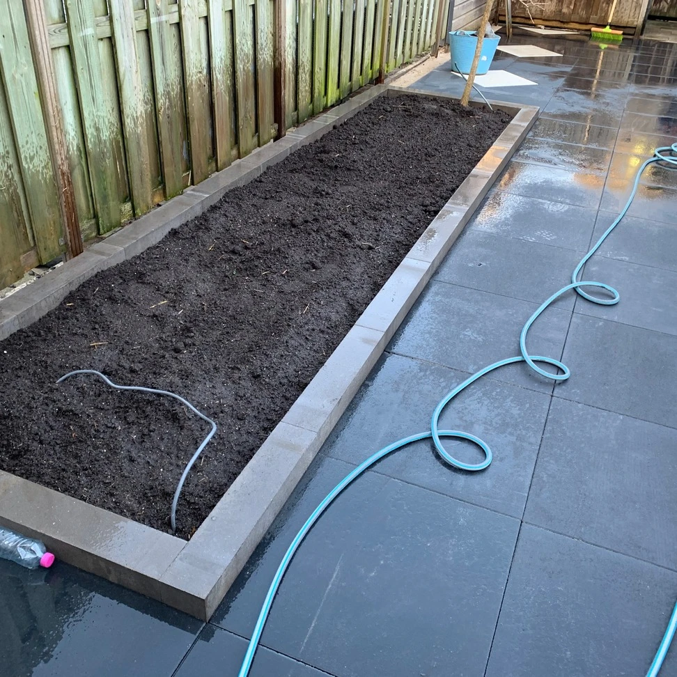 Verhoogde border in een strak betegelde tuin