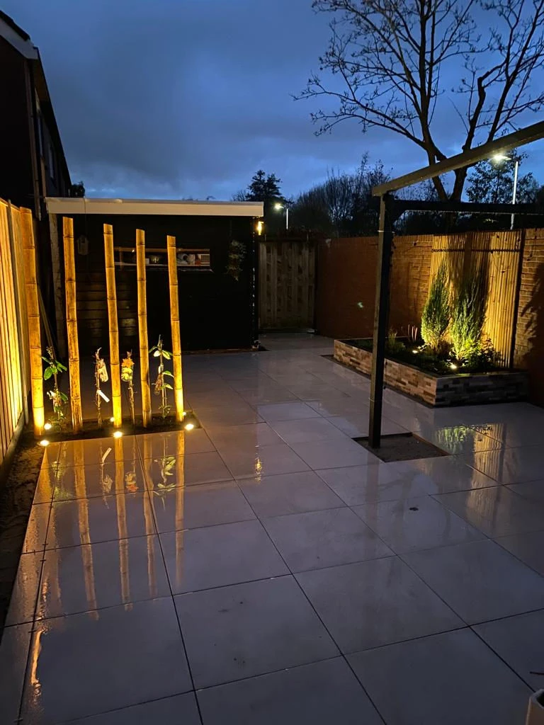 Overzichtfoto van de tuin 's avonds, met sfeervolle verlichting