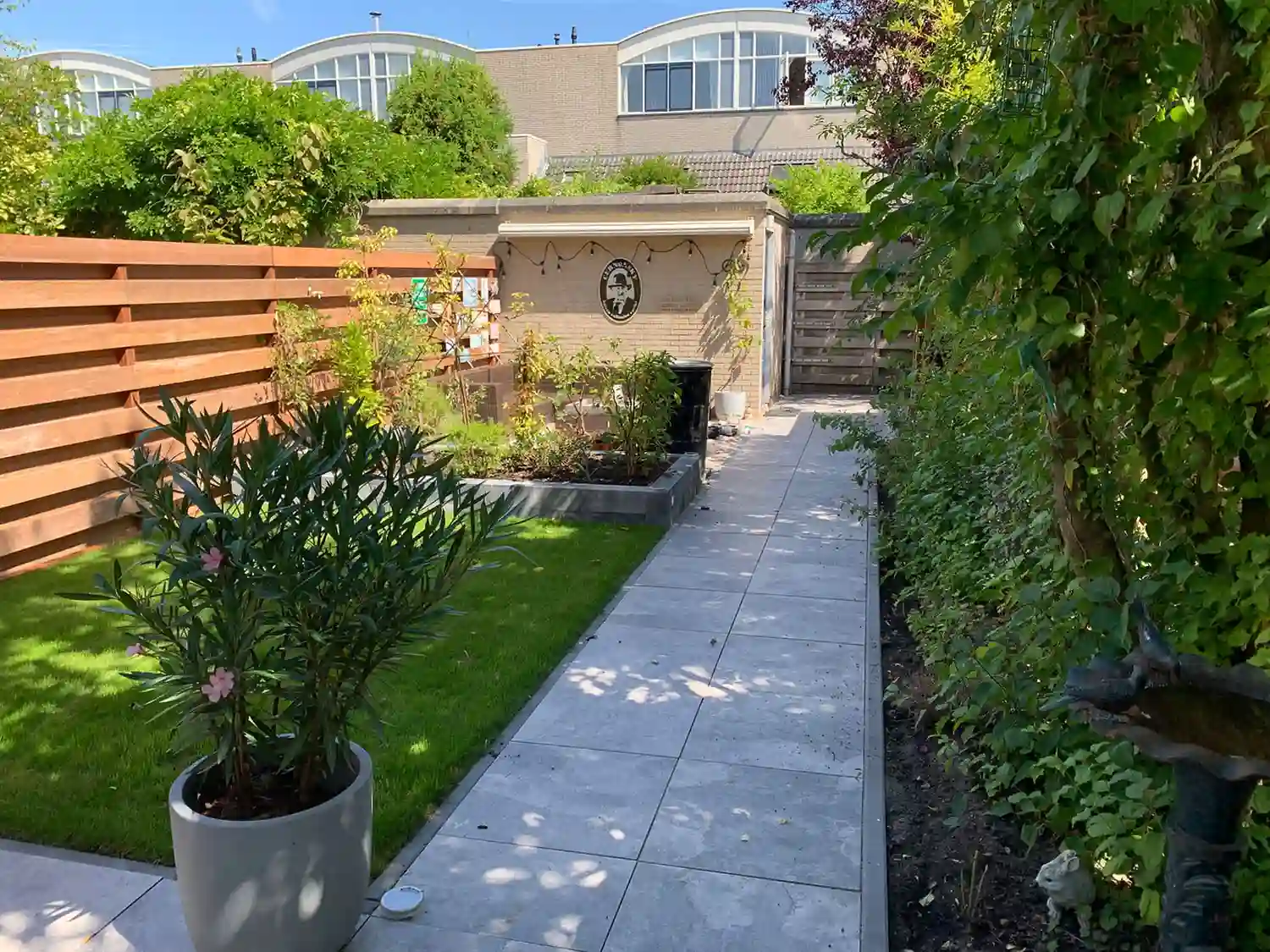 Moderne tuin met strak tegelpad, groen gazon en houten schutting